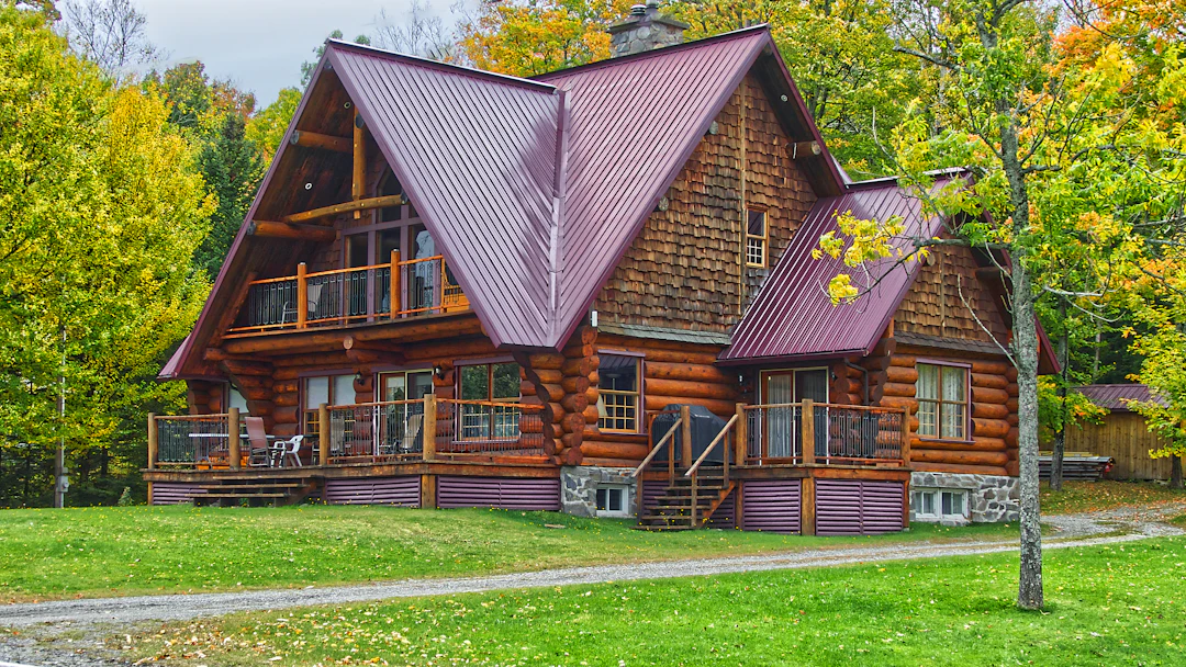 Chalet en bois rond entouré d’arbres d’automne