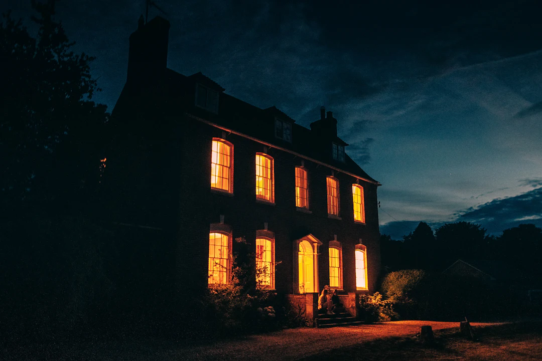 Maison de pierre aux fenêtres illuminées à la tombée de la nuit